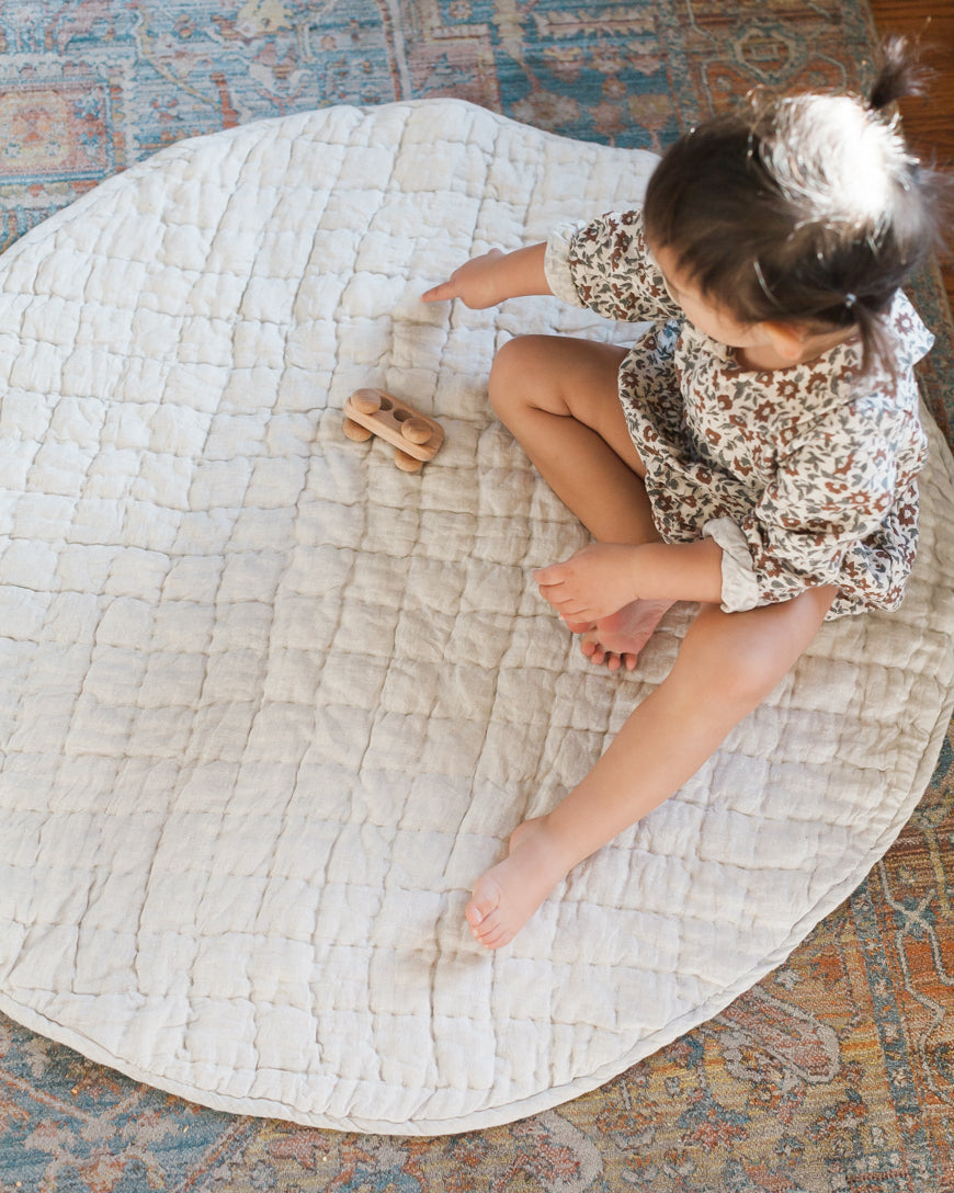 Child playing a quilted linen playmat