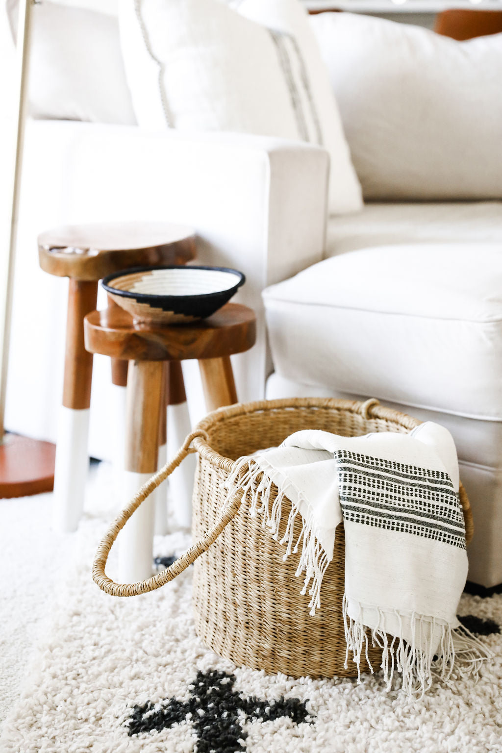 Woven basket with a blanket on a white couch in a cozy living room.