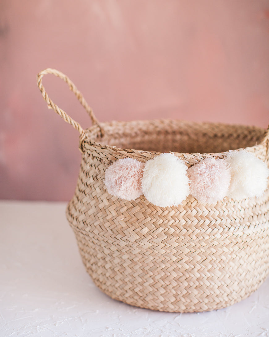 woven basket with white and pink poms and handle