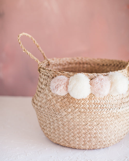 woven basket with white and pink poms and handle